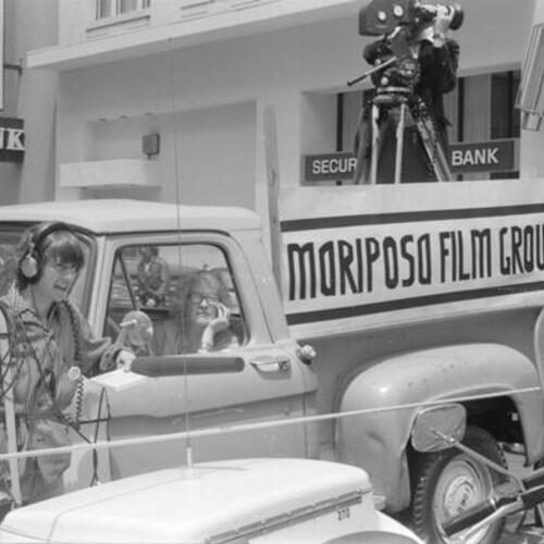 Veronica Selver, with sound equipment in production of Word is Out, stands next to Mariposa Film Group truck