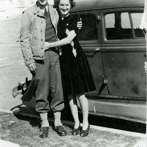 [Portrait of young couple standing next to a car]