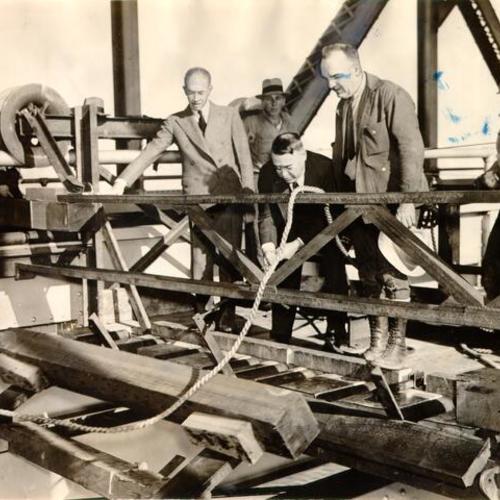 [Charles E. Andrew putting the first redwood tie into place for the San Francisco-Oakland Bay Bridge electric railway system]
