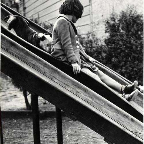 [Dolores is followed by Poncho the dog down a slide in the childrens playground at Golden Gate park]