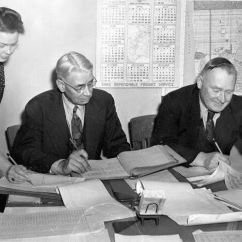 [Dolores Holter, Eugene W. Clisbee and Joseph D. Brogan working on streetcar and bus schedules]