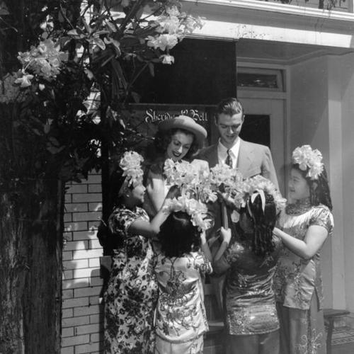[Four young girls, dressed in costume, presenting daffodils to a couple on Maiden Lane]