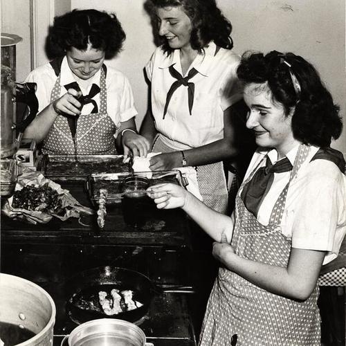 [Camp Fire Girls Gail Beach, Barbara Birdsall and Darlene Richter practicing at their clubhouse for the better breakfast campaign]