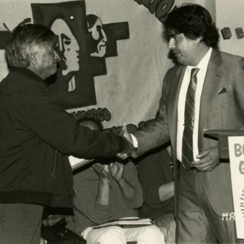 [Cesar Chavez, UFW president and president of La Raza shaking hands at SFSU Student Union]