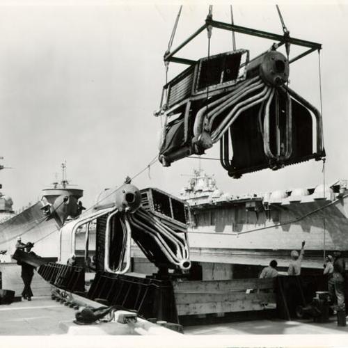 [Condensers from the USS INDEPENDENCE being hoisted onto a barge at San Francisco Naval Shipyard]