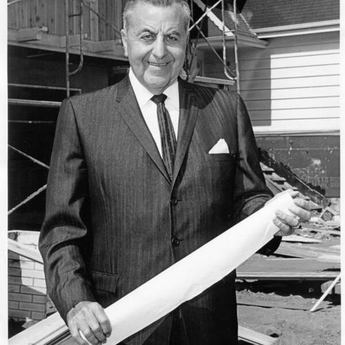 [Real estate developer, Henry Doelger, standing in front of a structure under construction]