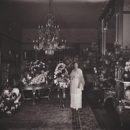 Person standing with floral arrangements in Victorian home 