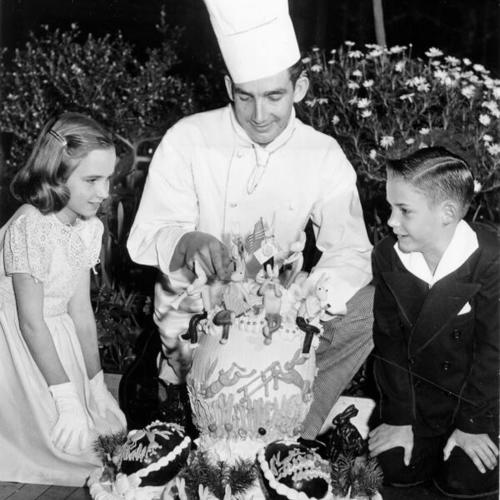 [Sally and Larry McCune watching pastry chef Roderick McDonald prepare an Easter egg at the Palace Hotel]