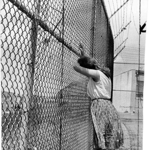 [Unidentified girl staring through a fence at the Youth Guidance Center]