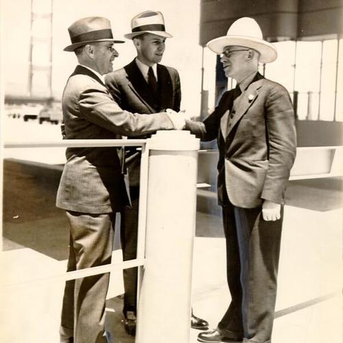 [James Reed and Ray West awarding R. C. Harold  the honor of being the "first commuter" on the Golden Gate Bridge]