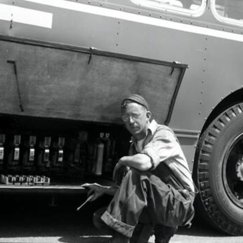 [Portrait of Shopman John Gerrard Graham repairing switchgroup of trolley coach 556 at Potrero Yard]