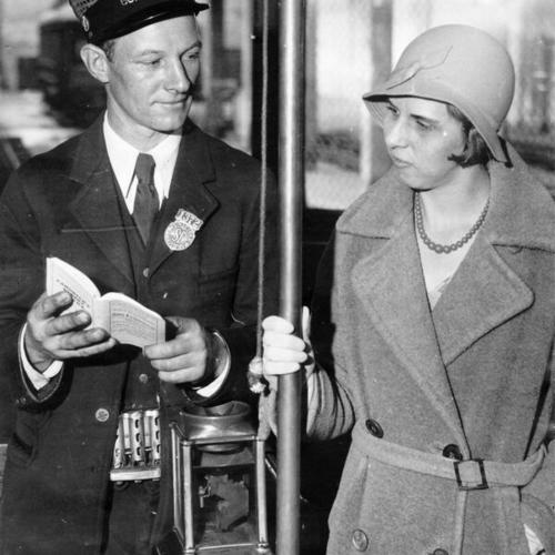 [Municipal Railway streetcar conductor Will Hage looking at a new street guide with passenger Viletta Willison]