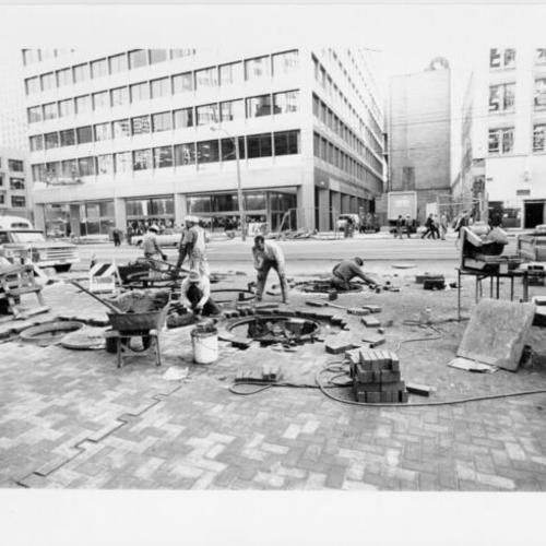 [Construction workers laying brick along the sidewalks of Market Street]
