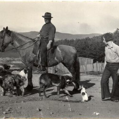 [Two unidentified people with four dogs and a horse in Visitacion Valley]
