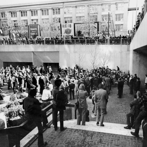 [Crowd gathered for a ceremony in Hallidie Plaza]