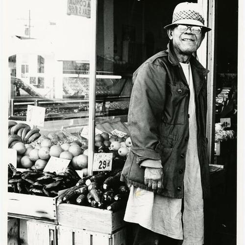 [Man standing in front of a Mission Street market]