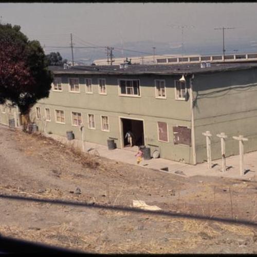Children exiting building with broken windows and withered hillside