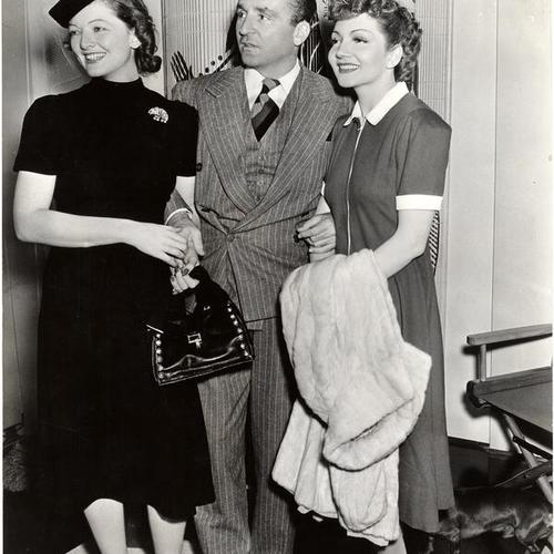[Myrna Loy, her husband Arthur Hornblow, Jr. and Claudette Colbert visiting a Cecil B. De Mille set in Hollywood]