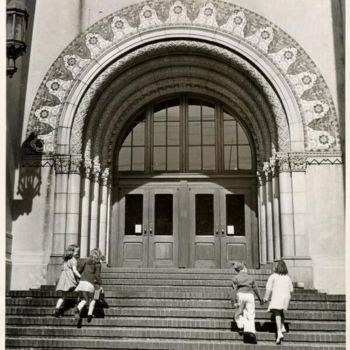 [Four children walking up the steps at the entrance to John Muir School]