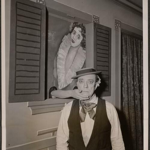 Buster Keaton in hat with hands coming through the window holding his face in "Silent Partner"