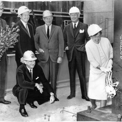 [Mrs. Fred McPherson breaking a bottle of champagne at a "launching" ceremony during the construction of a 43-story Wells Fargo Bank building at Sutter and Montgomery streets]