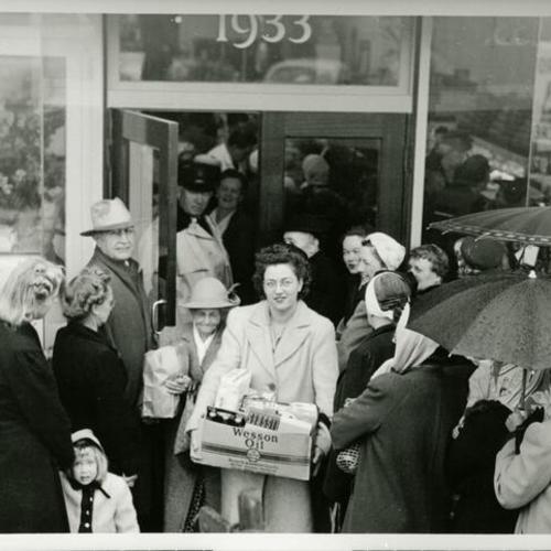 [Grand opening and entrance of Bowcock's Market. Woman carries a Wesson Oil box.]