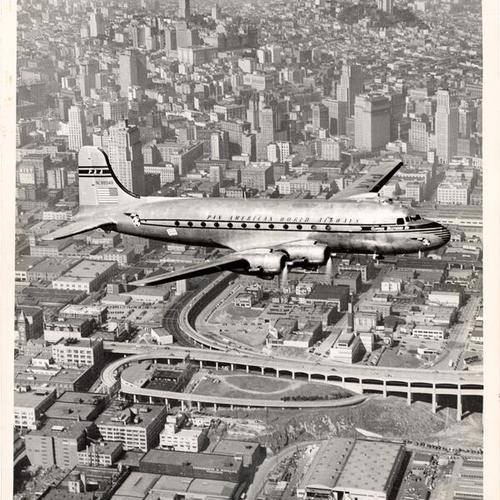 [Pan American World Airways airplane flying over office buildings]