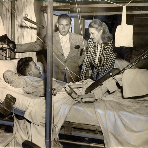 [Singers Bing Crosby and Dinah Shore visiting a wounded veteran at Letterman General Hospital]