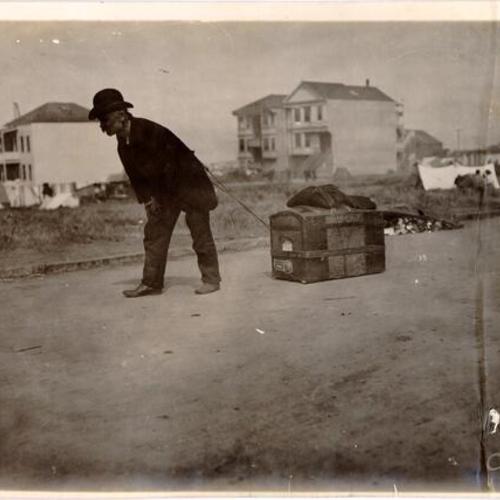 [Refugee dragging a chest with his possessions]