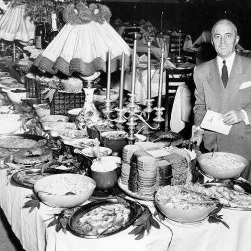 [Pat Fracchia, manager of Rickey's Town House restaurant, standing next to the smorgasbord table]