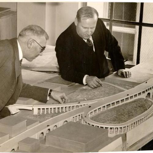 [Architect Timothy L Pflueger and Chief Engineer C. H. Purcell looking at a model of an approach to the San Francisco-Oakland Bay Bridge]