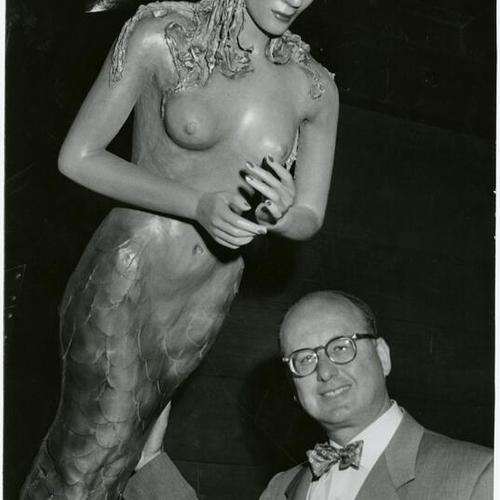 [Joe Byrnes, Bernstein's Manager, standing next to a mermaid statue]