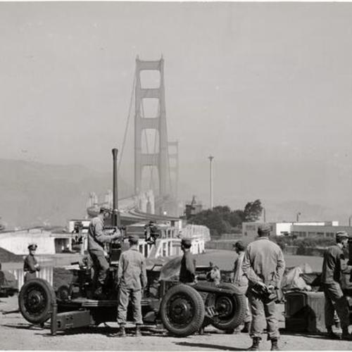[Gun crew of Battery C, 60th Anti-Aircraft Artillery Battalion at Fort Scott "tracking" a plane as it flies over the Golden Gate Bridge during a training exercise]