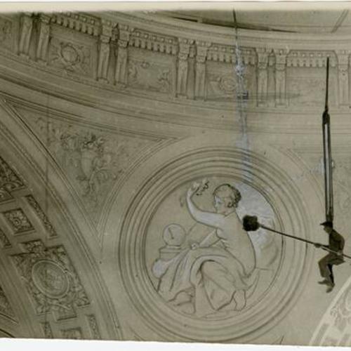 [Man cleaning a figure of a women engraved onto the wall of the Rotunda, City Hall]