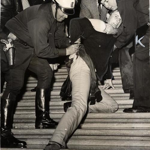 [Demonstrator fighting against being propelled down the marble steps of City Hall in the grip of two officers during the House un-American activities hearing]