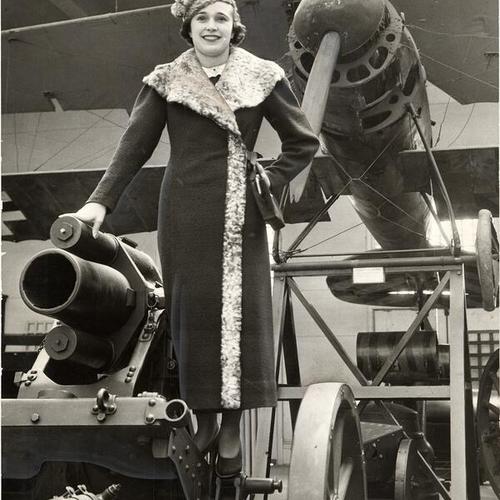 [Unidentified woman posing with military equipment at De Young Museum gallery exhibit of World War I trophies