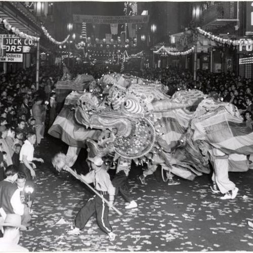 [Crowds gather to watch a Chinese dragon writhing through the streets of Chinatown]