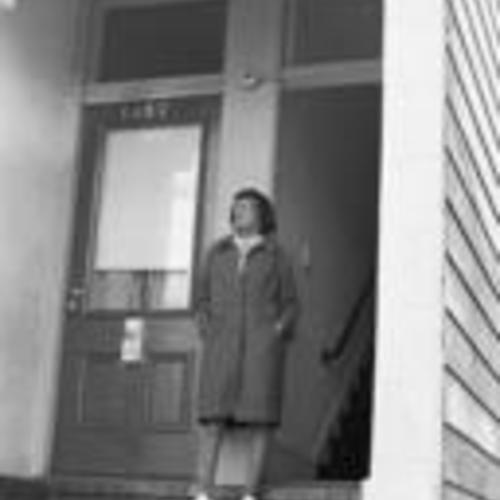 [Unnamed resident of the Western Addition redevelopment stands at doors of house numbers 1357 and 1359, street unknown]
