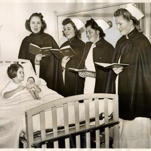 [Group of nurses at St. Joseph's Hospital singing Christmas carols to four-year-old patient Lorene Carroll]
