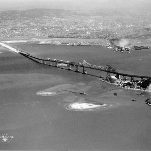 [Aerial view of cantilever section of Bay Bridge with Oakland in background]