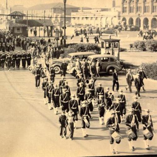 [Marching band and servicemen passing by spectators in the opening day celebration parade for San Francisco-Oakland Bay Bridge]