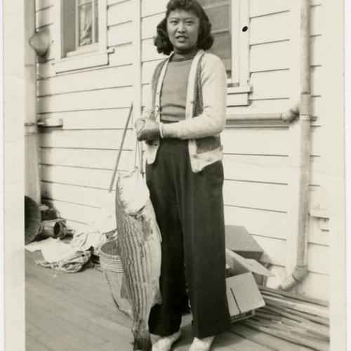 [Unidentified woman holding a fish in Visitacion Valley]