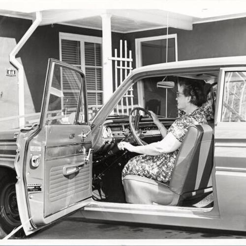[Woman sitting behind the steering wheel of an automobile at San Francisco State College]