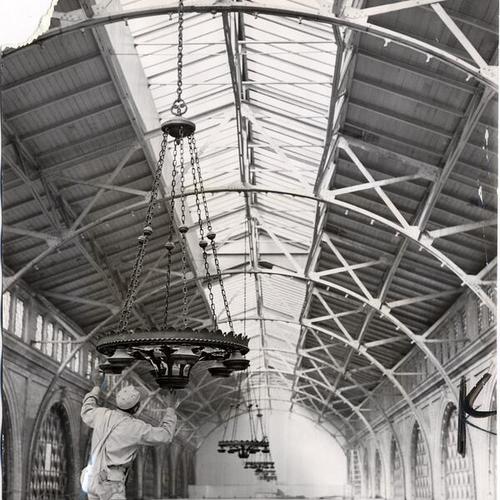 [Worker inspecting a light fixture during renovation of the Ferry Building]