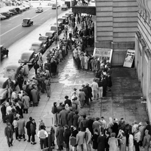 [Football fans jamming the sidewalk in front of the Civic Auditorium for tickets]