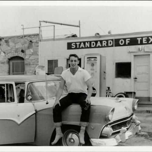 Harvey Milk sitting on car at gas station in Texas