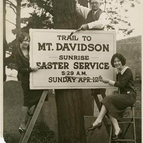 [Clarence F. Pratt, Miss Helyn Dawley and Miss Lucille Rogers with a sign on Mount Davidson]