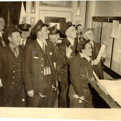 [Municipal Railway employees reading a bulletin board in the carbarn at 2600 Geary Boulevard]