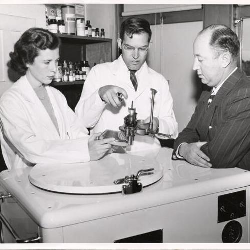 [Dr. William Hovanitz demonstrating a laboratory procedure to Marco F. Hellman with the assistance of graduate student Virginia Madden at the University of San Francisco]