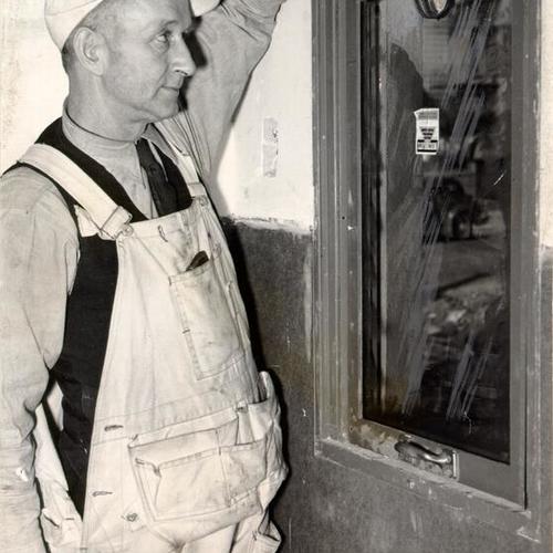 [Unidentified worker pointing to a bullet-proof window in one of two guard rooms at the U. S. Mint in San Francisco]